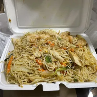 a take out container of noodles and chicken