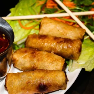 a plate of fried spring rolls with dipping sauce