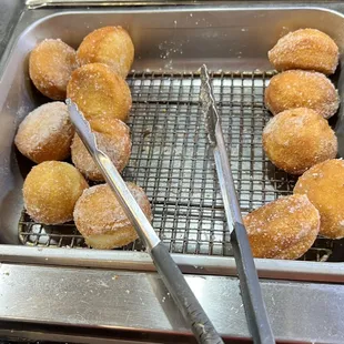 a tray of doughnuts and tongs