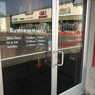a business hours sign in the window
