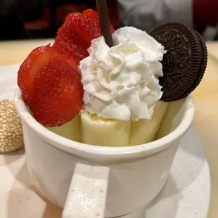 a bowl of ice cream, strawberries, and cookies