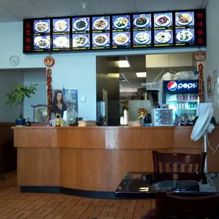 a restaurant counter with a menu on the wall