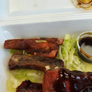 a plate of ribs, lettuce and sauce