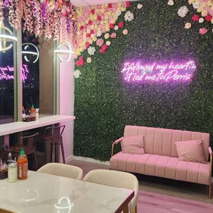a room with a pink sofa and a floral wall