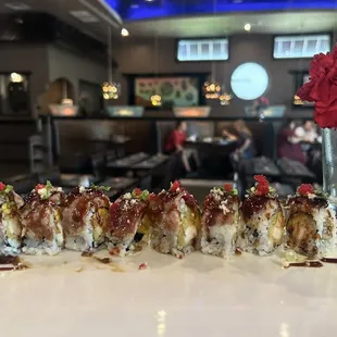 Dynamite Roll  Inside shrimp tempura,mango,cucumber and red onion.Topped with grilled steak,eel sauce,crunch,tobiko and scallion.