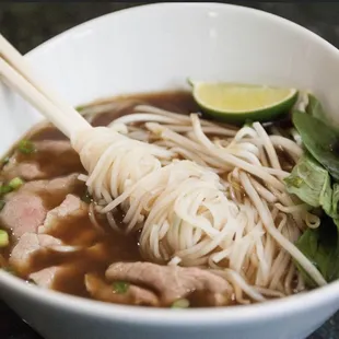 a bowl of noodle soup with chopsticks