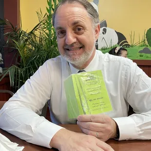 a man sitting at a table holding a book