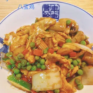 a plate of stir fried chicken with peas and carrots