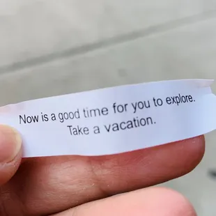 a hand holding a piece of paper that says now is a good time for you to explore take a vacation