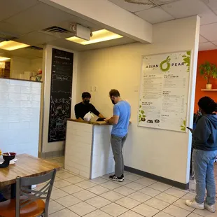 two people standing at a counter in a restaurant