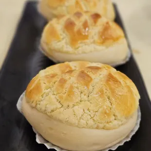 three rolls of bread on a black plate