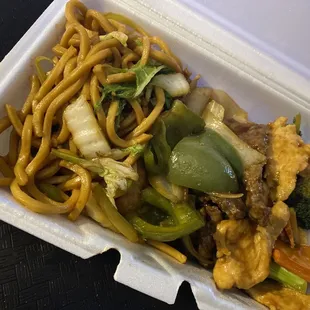 a take out container with noodles and vegetables