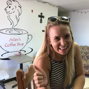 a woman sitting at a table giving a thumbs up