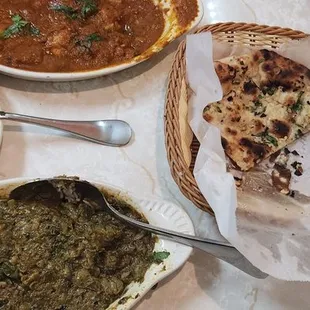 Chicken curry in the back, garlic nann, rice and i dont know what the lamb plat is called but the one with tomato .