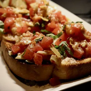 a plate of toasted bread topped with tomatoes