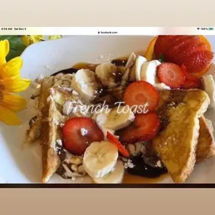 a plate of french toast with bananas, strawberries, and walnuts