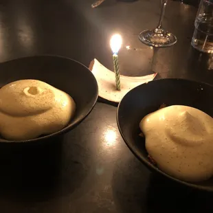 two bowls of food with a candle in the background