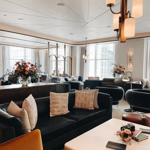 a large living room with black couches and a dining table