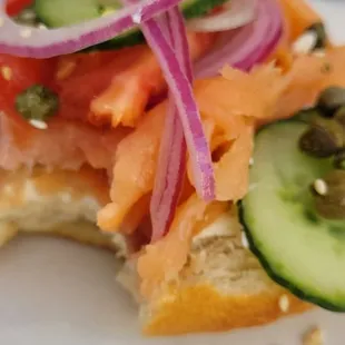 a sandwich with salmon, cucumbers and capers