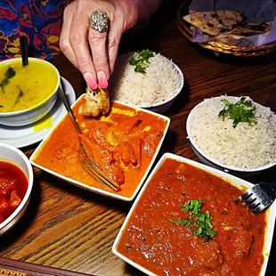  person dipping a piece of bread into a bowl of curry