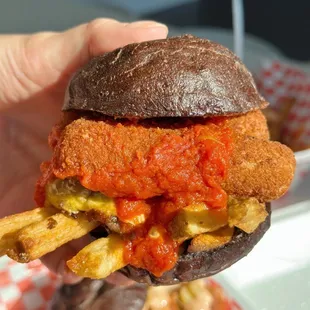 a hand holding a sandwich and fries