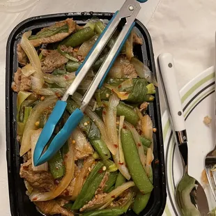 a plastic container with a stir fry in it