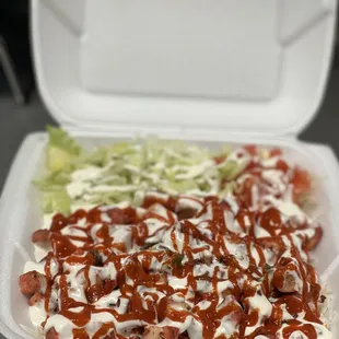 a takeout container with a salad and ketchup