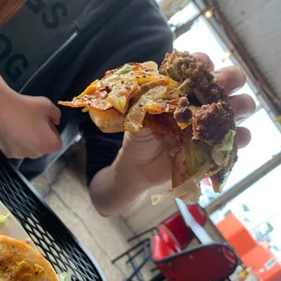 a hand holding a piece of pizza