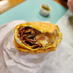 Breakfast burrito with bacon. Comes with cheese, potatoes, choice of meat &amp; eggs. Mid.