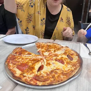 a woman sitting at a table with a pizza