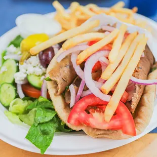 a pita sandwich with french fries and salad