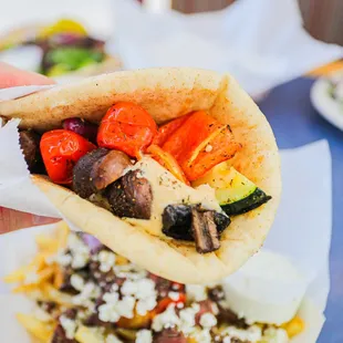 a hand holding a pita filled with vegetables