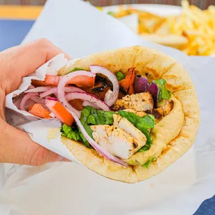 a hand holding a pita sandwich