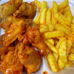 chicken wings and french fries in a styrofoam container