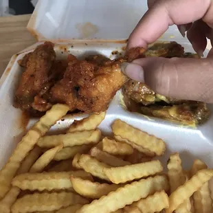 a hand picking up a piece of fried chicken