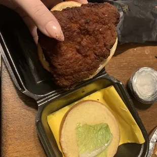 a hand grabbing a fried chicken sandwich