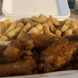 chicken wings and french fries in a styrofoam container