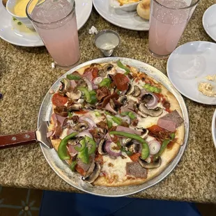 a pizza with pepperoni, mushrooms, peppers, and other toppings