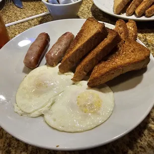 Two eggs over medium with sausage links and wheat toasts