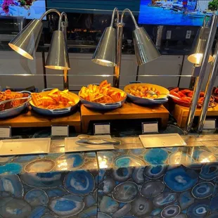 Buffet area with waffles and donuts and all the breakfast foods you would want on a vacation