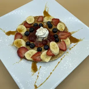 a waffle topped with strawberries, bananas, and blueberries