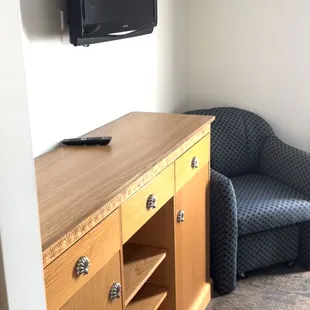 The desk in the room with lounge chair and another small TV.