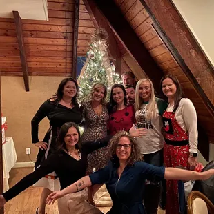 a group of women posing in front of a christmas tree
