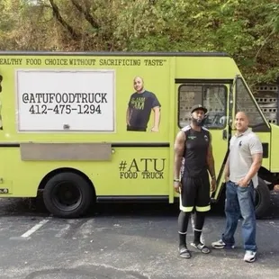 two men standing in front of a food truck