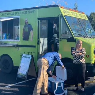 three people standing in front of a food truck