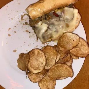 Steak and Cheese sandwich with potato chips.