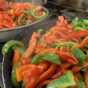 peppers being cooked in a frying pan