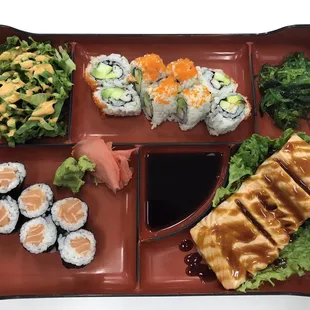 a tray of sushi and vegetables