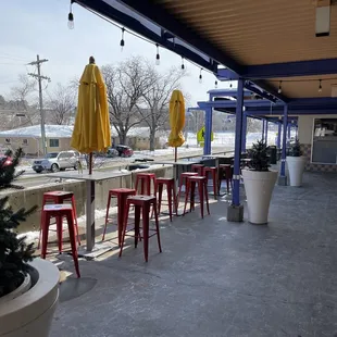 a patio with red stools and yellow umbrellas