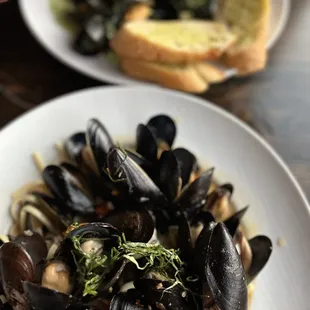 Mediterranean mussels with pasta underneath and other one is the pesto mussels with crispy garlic bread.